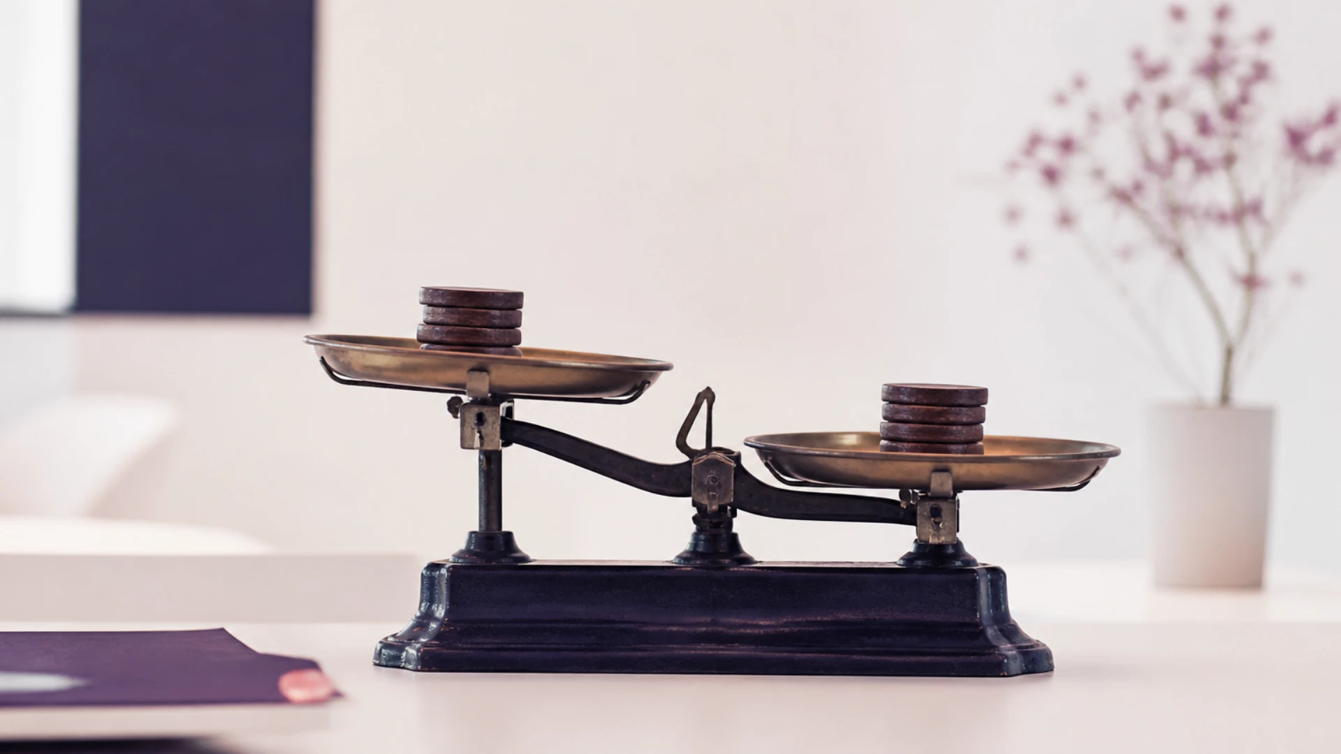 Balance à deux plateaux en léger déséquilibre chargée de jetons de bois