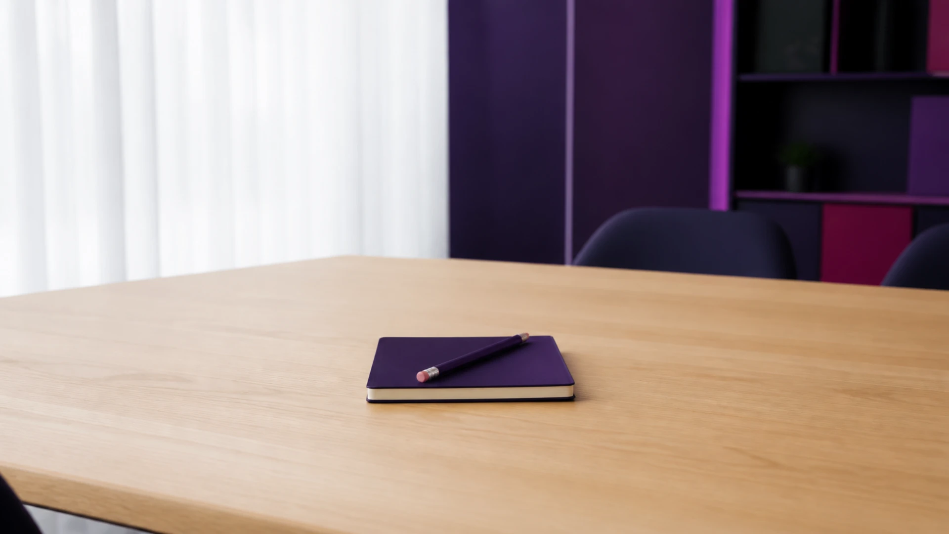 Carnet fin seul au centre d’une grande table vide avec un crayon posé en travers