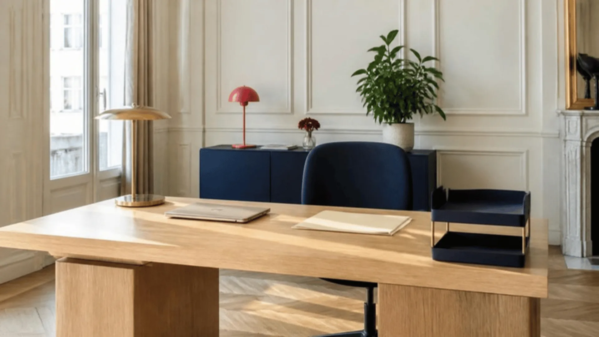 Bureau rangé avec ordinateur portable fermé, bannette vide et une chemise cartonnée posée