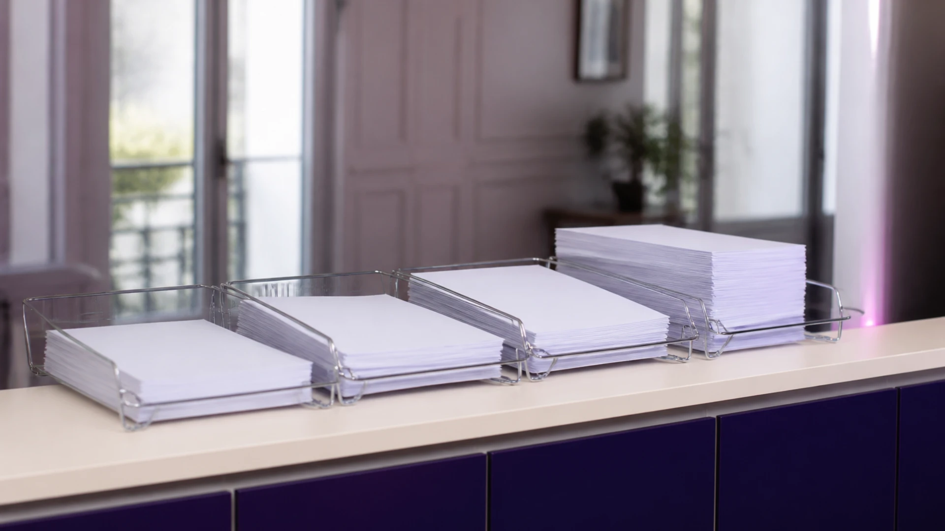 Bacs à courrier alignés contenant des piles de feuilles vierges, illustrant la collecte des variables de paie