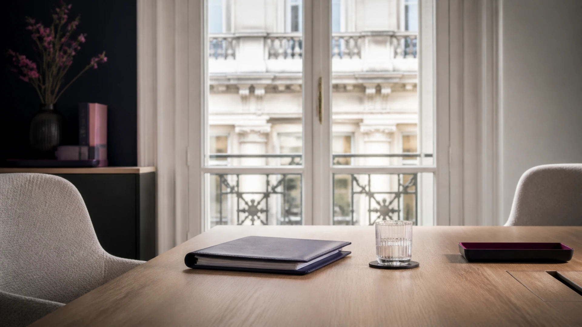 Bureau de gestion d’actifs haussmannien avec parapheur fermé et fauteuils face à la fenêtre