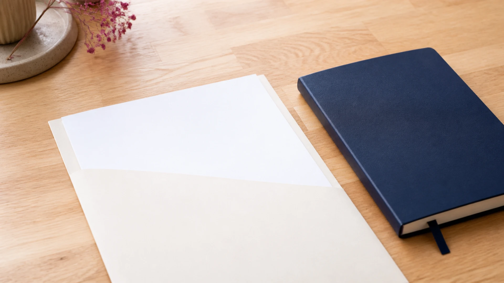 Facture vierge dans une chemise crème posée à côté d'un carnet de croquis fermé