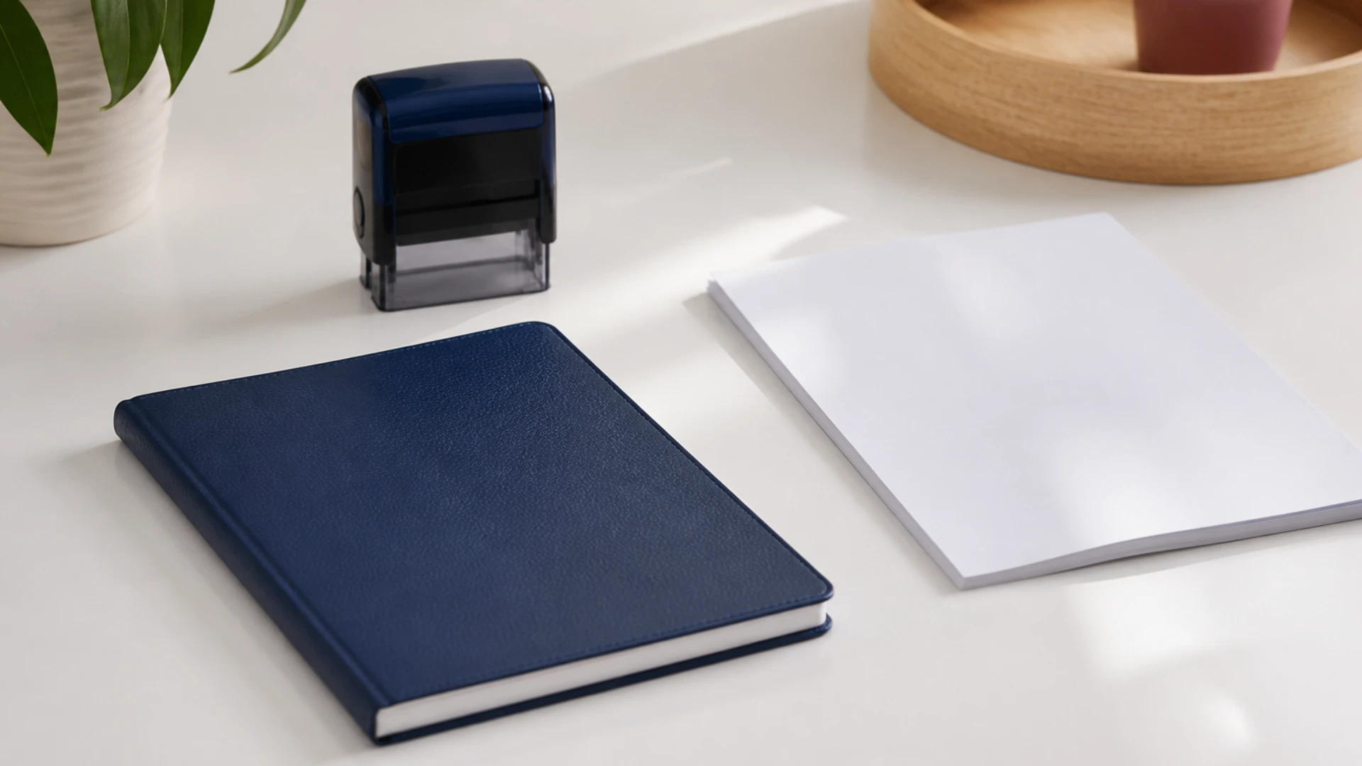Carnet de rendez-vous fermé et tampon encreur posés sur un plan de travail blanc