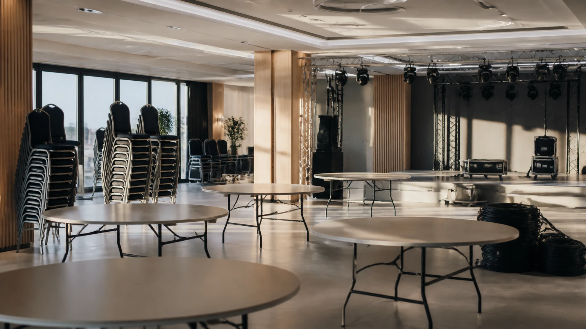 Salle de réception en cours d'installation avec tables rondes nues et structure de scène
