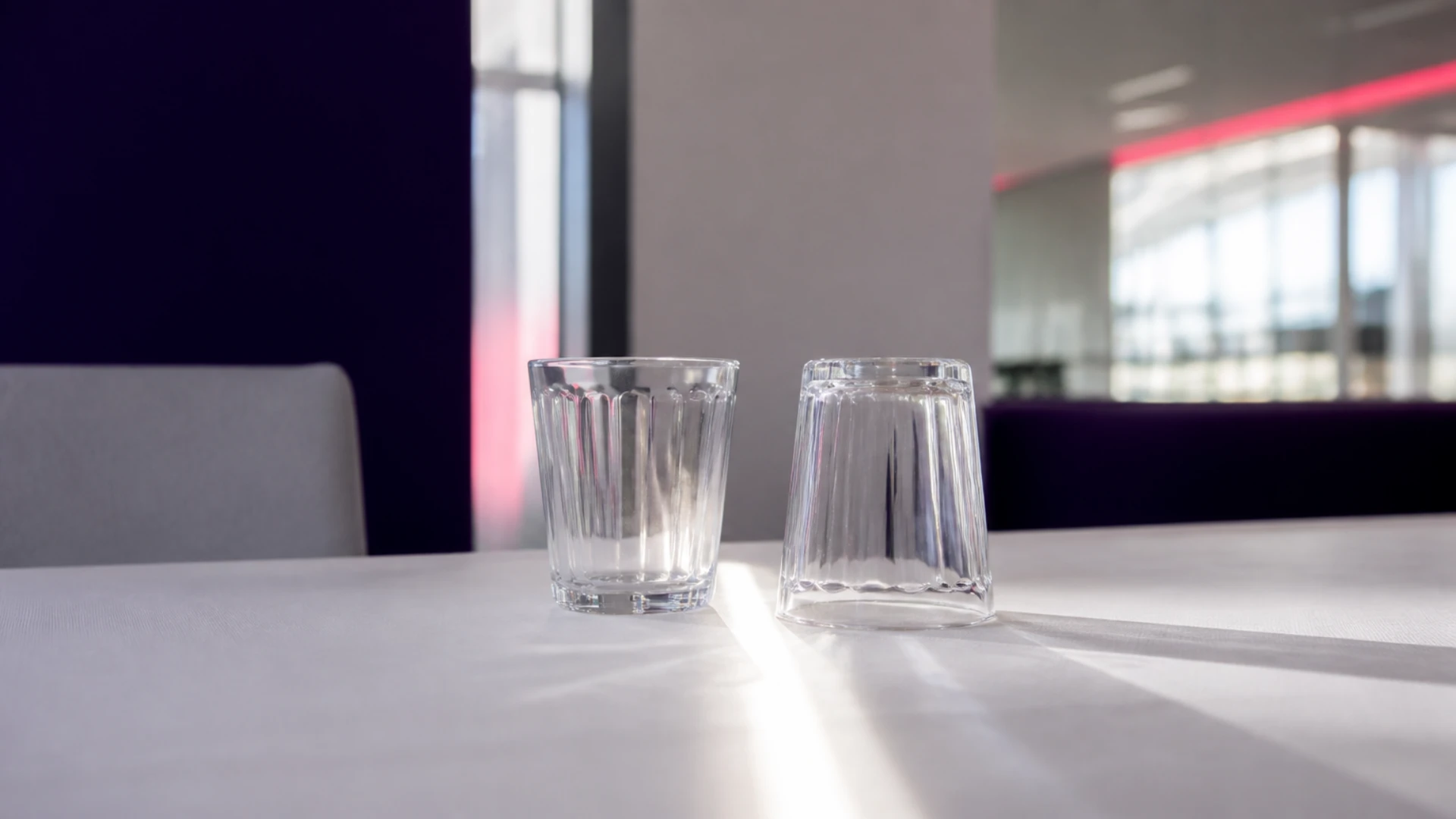Deux verres identiques côte à côte, l’un droit et l’autre retourné, séparés par une ligne de lumière