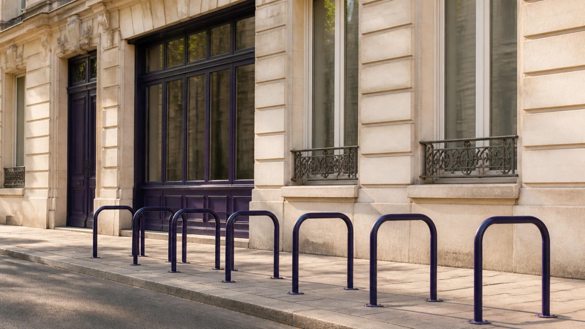 Arceaux de stationnement à vélos vides alignés devant une façade haussmannienne