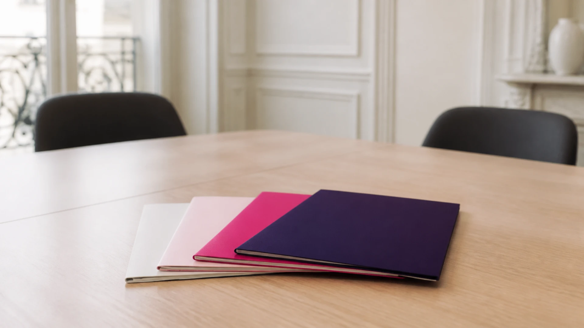 Quatre dossiers de couleurs différentes disposés en éventail sur une table de réunion